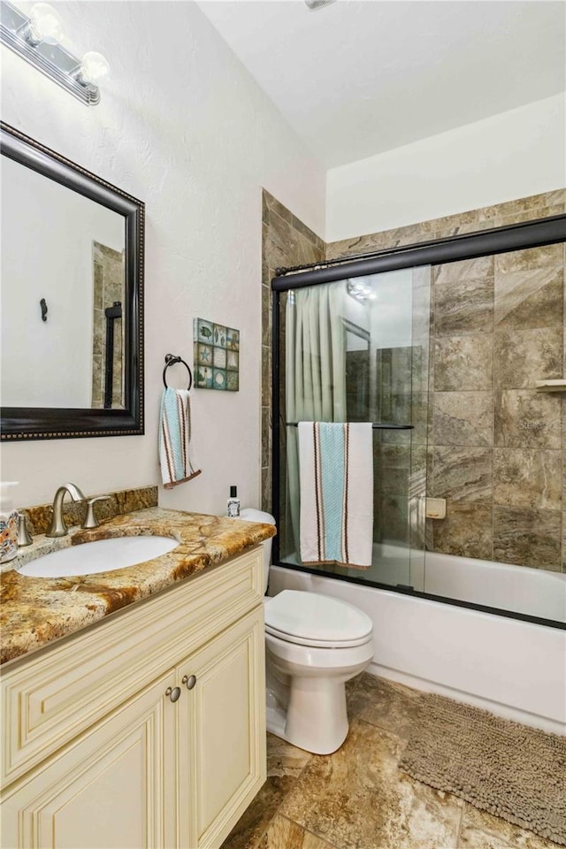 full bathroom featuring shower / bath combination with glass door, vanity, and toilet