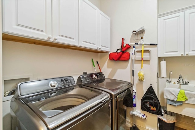 clothes washing area featuring cabinets and washer and dryer