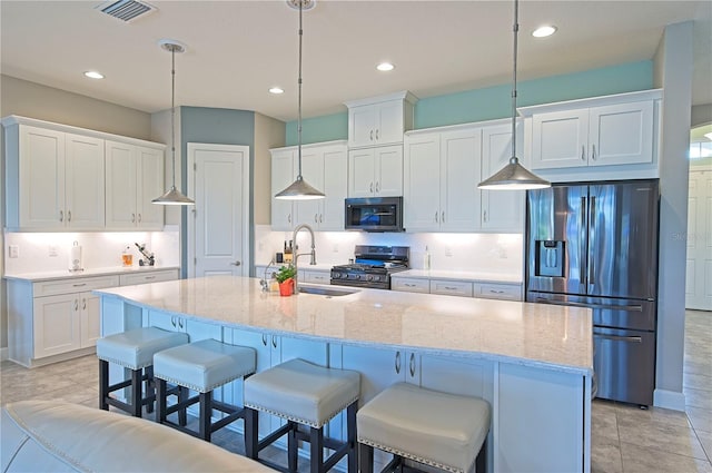 kitchen featuring sink, an island with sink, decorative light fixtures, white cabinetry, and stainless steel appliances