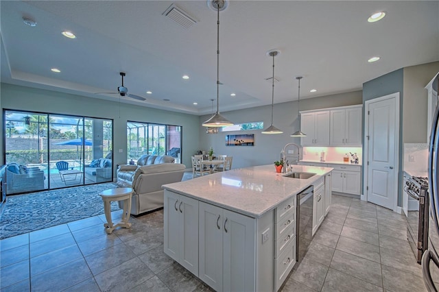 kitchen featuring a center island with sink, sink, ceiling fan, appliances with stainless steel finishes, and white cabinetry