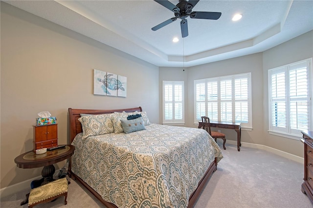 carpeted bedroom featuring ceiling fan and a tray ceiling