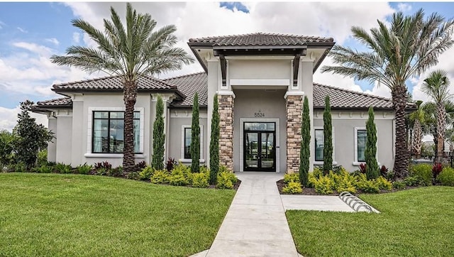 mediterranean / spanish-style home with a front yard and french doors