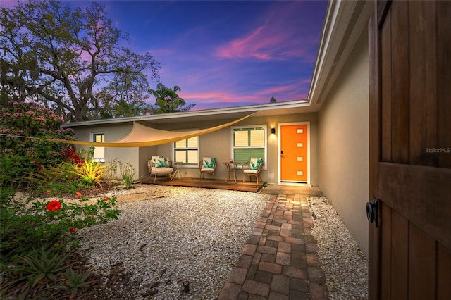 back house at dusk featuring a patio area