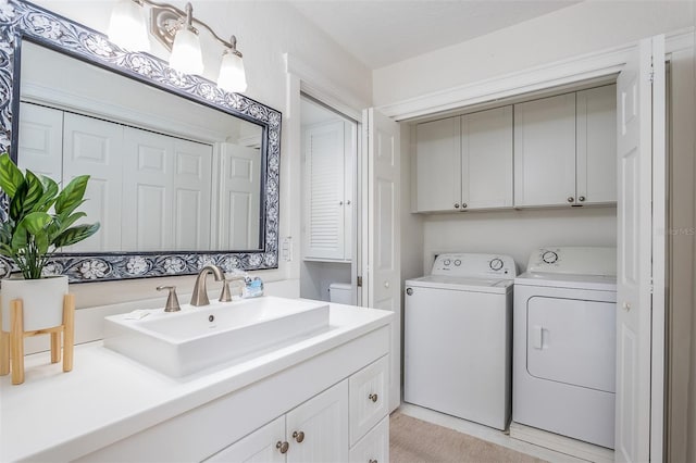 laundry area featuring washing machine and clothes dryer, sink, and cabinets