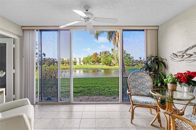 sunroom / solarium featuring ceiling fan and a water view