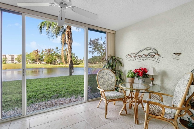 sunroom with ceiling fan and a water view