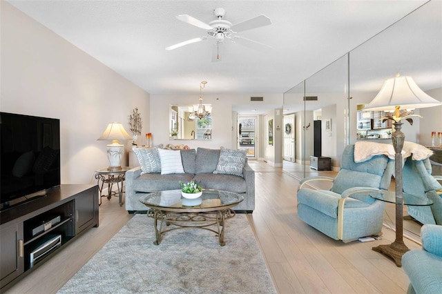 living room with ceiling fan with notable chandelier and light wood-type flooring