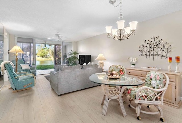 living room featuring ceiling fan with notable chandelier, light wood-type flooring, and expansive windows