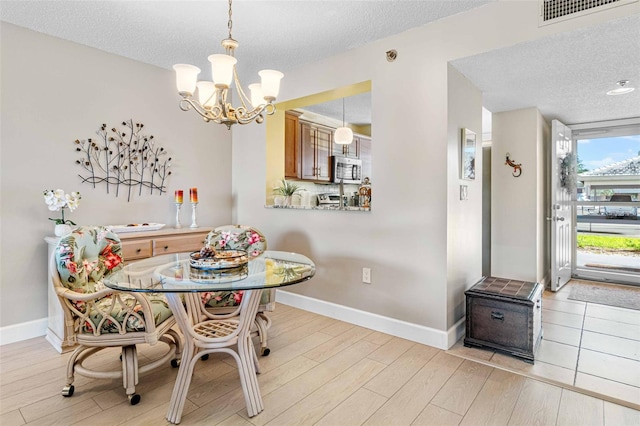 dining room with an inviting chandelier, light hardwood / wood-style floors, and a textured ceiling