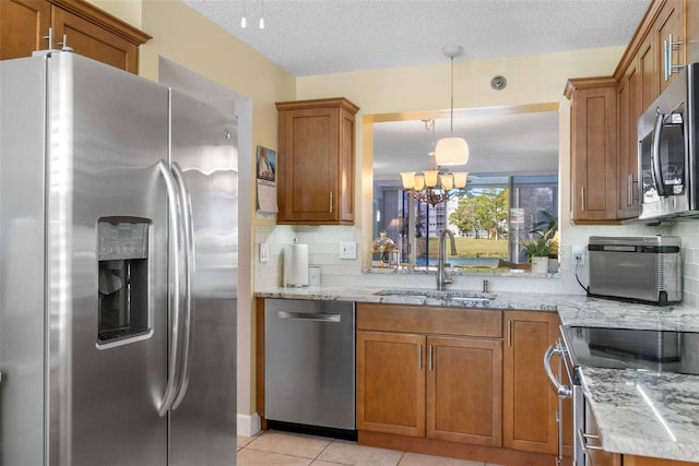 kitchen featuring stainless steel appliances, light tile patterned floors, a notable chandelier, pendant lighting, and sink