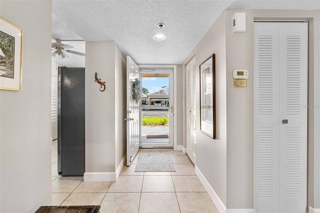 interior space featuring a textured ceiling, ceiling fan, and light tile patterned floors