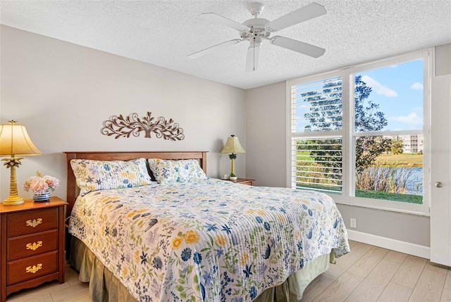 bedroom featuring a textured ceiling, ceiling fan, and light wood-type flooring