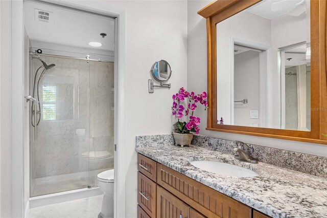 bathroom with toilet, a shower with door, and vanity