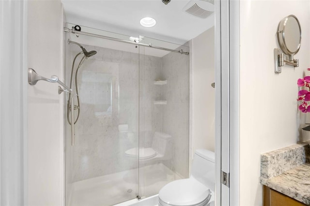 bathroom with walk in shower, vanity, and toilet