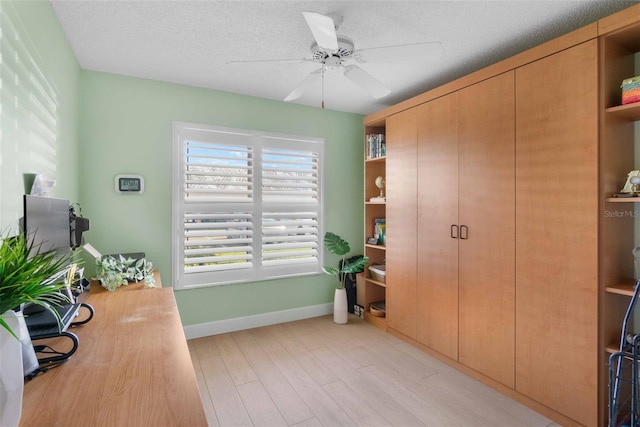 home office featuring a textured ceiling, ceiling fan, and light hardwood / wood-style flooring