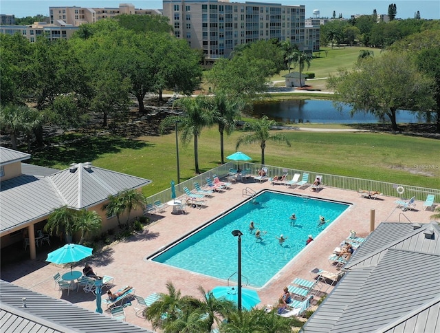 view of pool featuring a patio, a lawn, and a water view