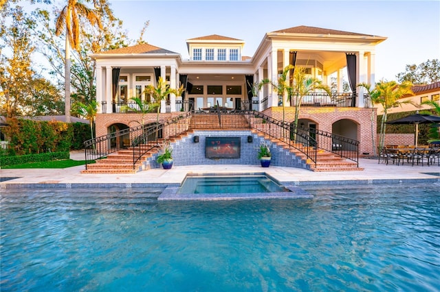 rear view of house featuring a swimming pool with hot tub and a patio area