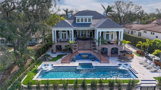 back of property with a swimming pool with hot tub, french doors, and a patio