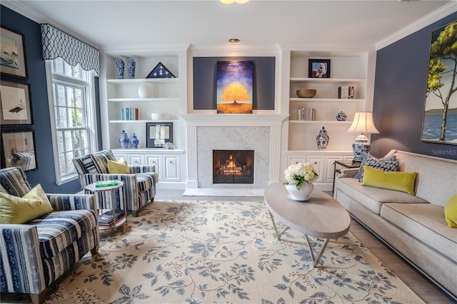 living room featuring crown molding, a fireplace, built in shelves, and hardwood / wood-style flooring