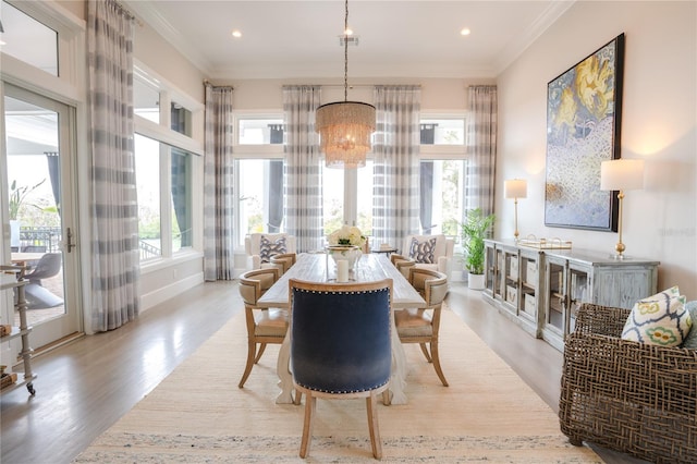 dining space with an inviting chandelier, light hardwood / wood-style flooring, ornamental molding, and plenty of natural light