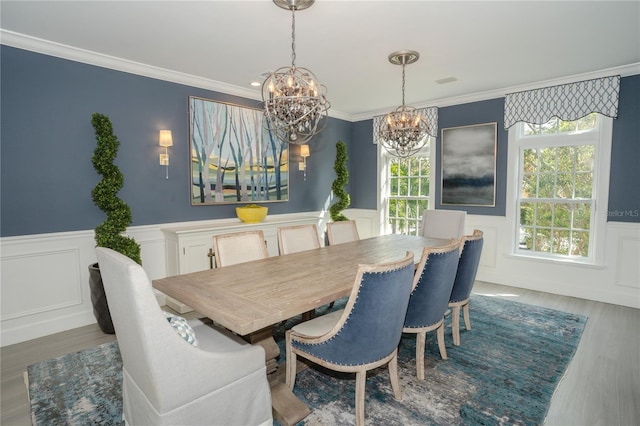 dining space featuring wood-type flooring, a notable chandelier, and crown molding