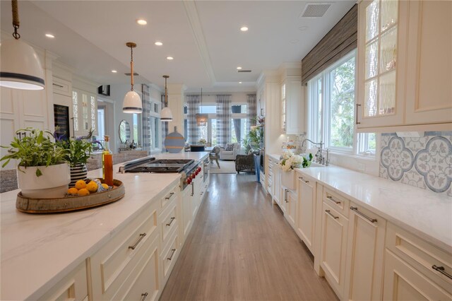 1541 Bay Point Dr, Sarasota, FL 34236 - kitchen featuring stainless steel gas stovetop, light wood-type flooring, glass insert cabinets, recessed lighting, and open floor plan