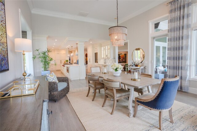 1541 Bay Point Dr, Sarasota, FL 34236 - dining room with light wood-style flooring, crown molding, a chandelier, and ornate columns