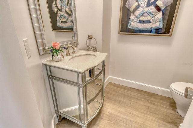 1541 Bay Point Dr, Sarasota, FL 34236 - half bath with baseboards, wood finished floors, vanity, and toilet