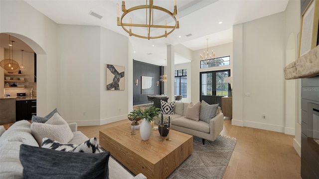 living room featuring light hardwood / wood-style flooring, a notable chandelier, and french doors