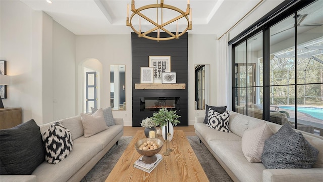 living room featuring hardwood / wood-style flooring, a chandelier, a raised ceiling, and a fireplace