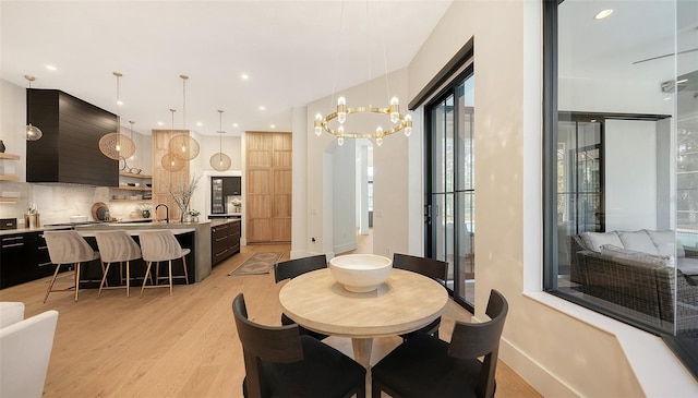 dining area featuring sink, light hardwood / wood-style floors, and an inviting chandelier