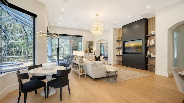 living room featuring built in features, a notable chandelier, and light wood-type flooring