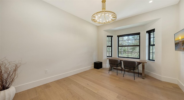 home office featuring light wood-type flooring, an inviting chandelier, and lofted ceiling