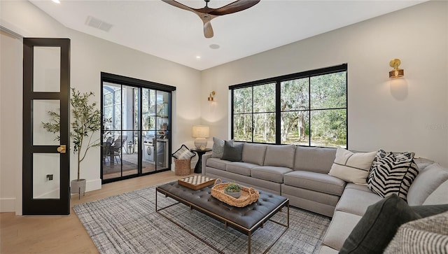 living room with ceiling fan, light hardwood / wood-style floors, and lofted ceiling