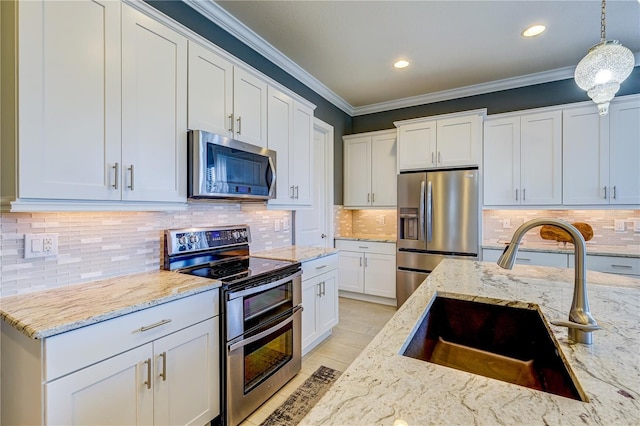 kitchen with decorative light fixtures, sink, white cabinetry, and stainless steel appliances