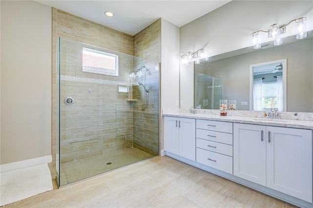 bathroom with ceiling fan, tile patterned floors, vanity, and a tile shower