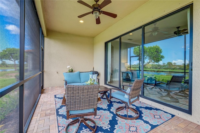 sunroom / solarium featuring ceiling fan and a water view