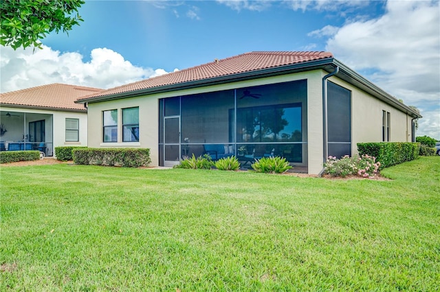 rear view of house featuring a yard and a sunroom