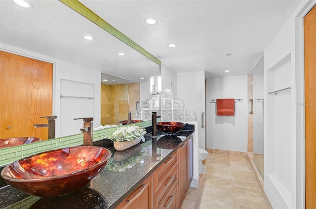 bathroom with tile patterned floors, vanity, toilet, and walk in shower