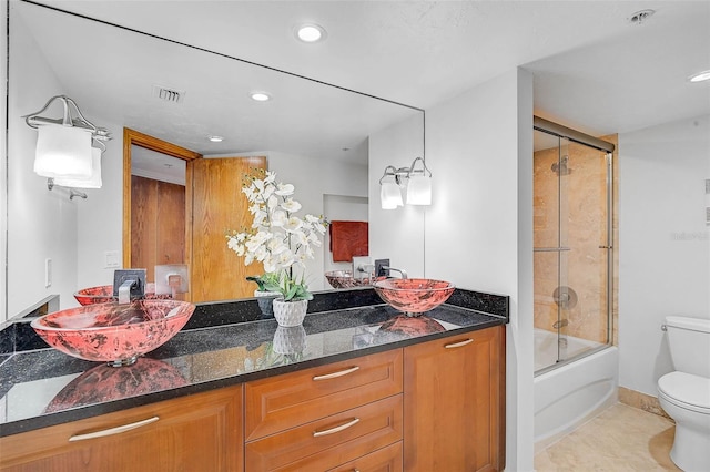 full bathroom featuring tile patterned floors, vanity, bath / shower combo with glass door, and toilet