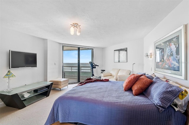 bedroom featuring carpet, a textured ceiling, access to outside, and a wall of windows