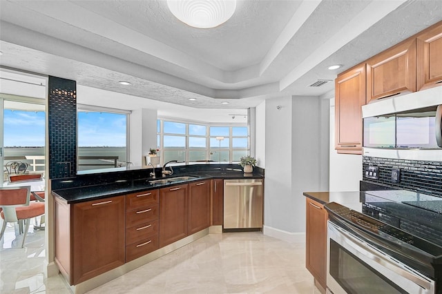 kitchen with sink, stainless steel appliances, tasteful backsplash, dark stone counters, and a textured ceiling