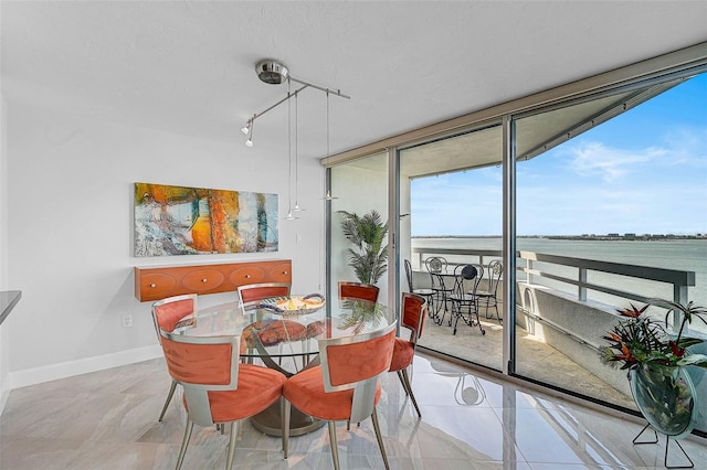 dining room with expansive windows, a water view, and track lighting