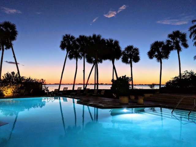 pool at dusk featuring a water view