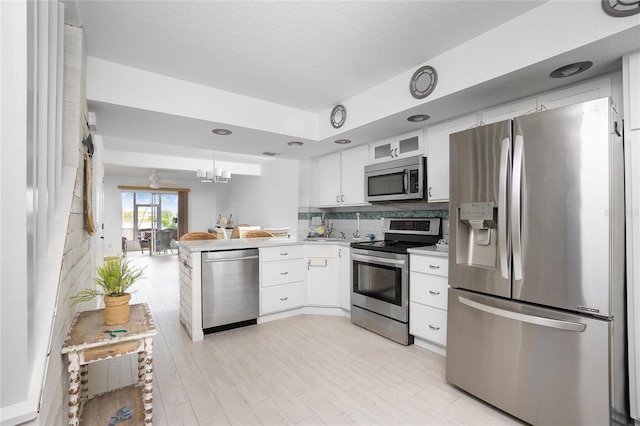 kitchen with white cabinetry, tasteful backsplash, pendant lighting, ceiling fan with notable chandelier, and appliances with stainless steel finishes