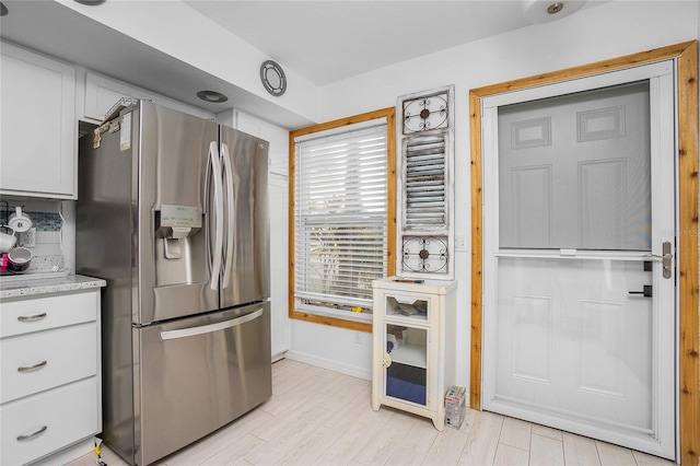 kitchen featuring light stone countertops, stainless steel refrigerator with ice dispenser, backsplash, and white cabinetry