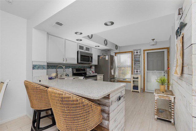 kitchen with white cabinets, a kitchen breakfast bar, stainless steel appliances, and kitchen peninsula