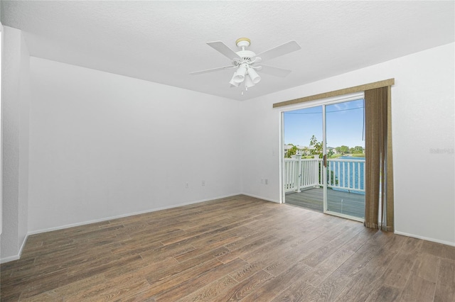 empty room with a textured ceiling, ceiling fan, and dark wood-type flooring