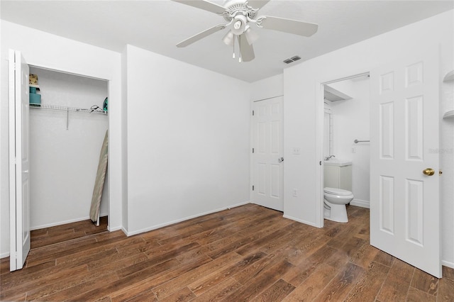 unfurnished bedroom featuring ceiling fan, a closet, dark wood-type flooring, and ensuite bath