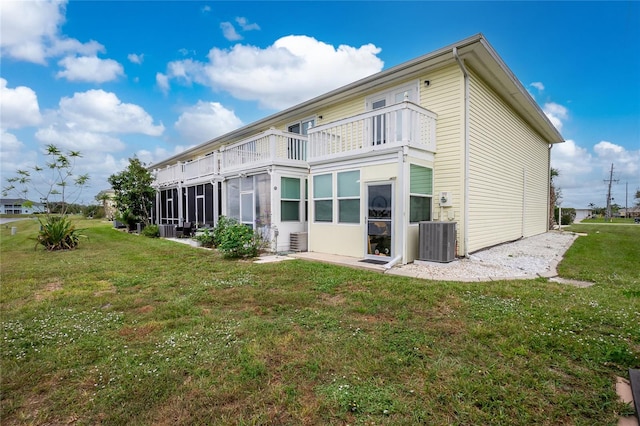 rear view of property featuring a yard, a balcony, a sunroom, and central air condition unit